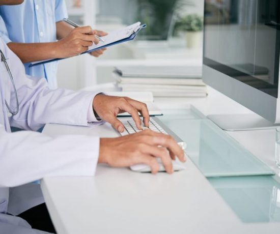 Cropped image of doctor working on computer at his table